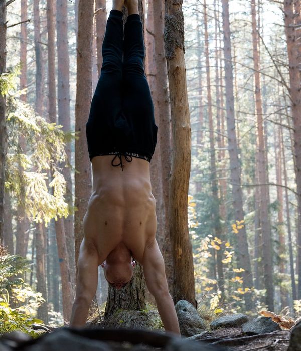 Man performing a controlled bodyweight strength exercise in a dark room.